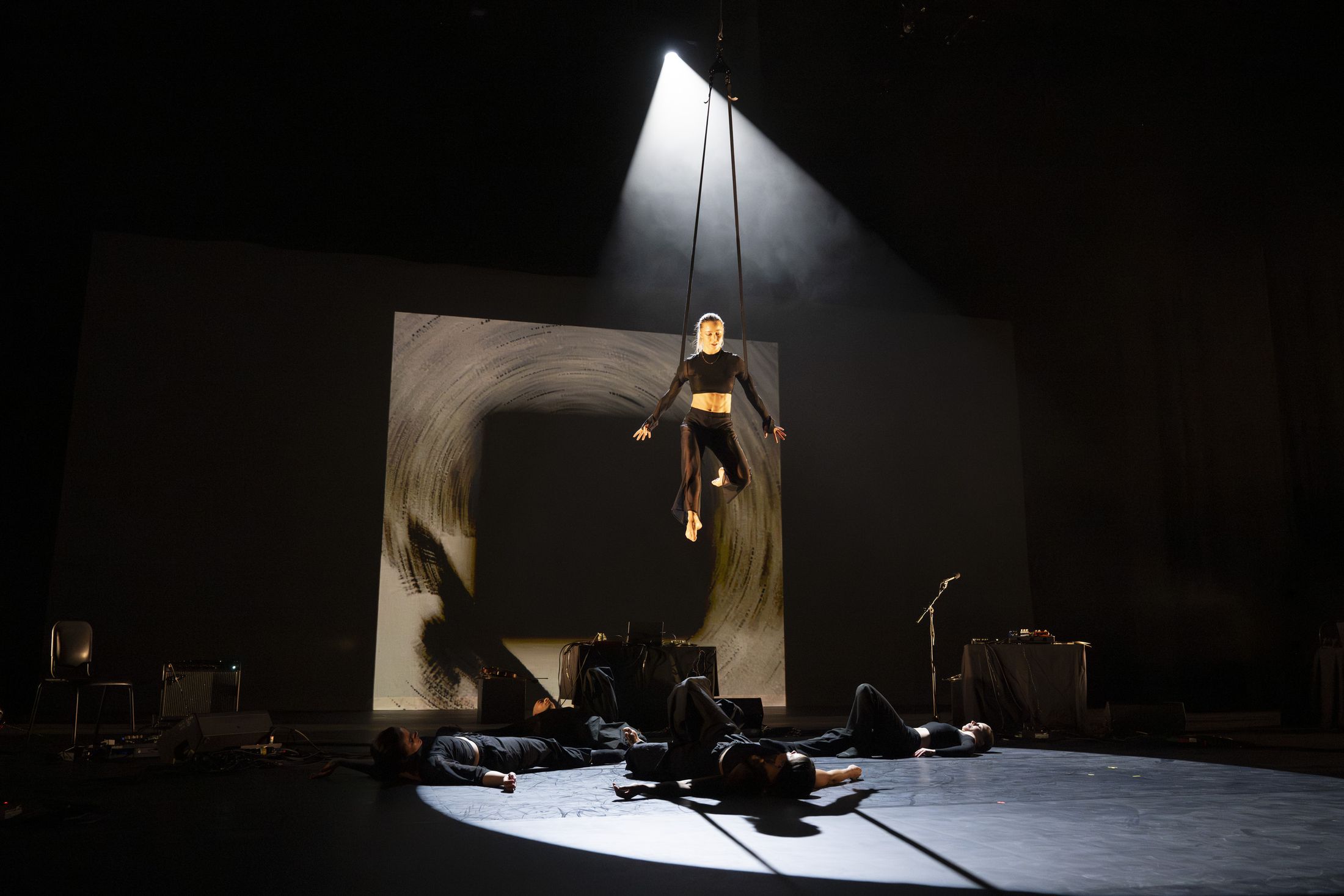 The aerialist above the circle of light