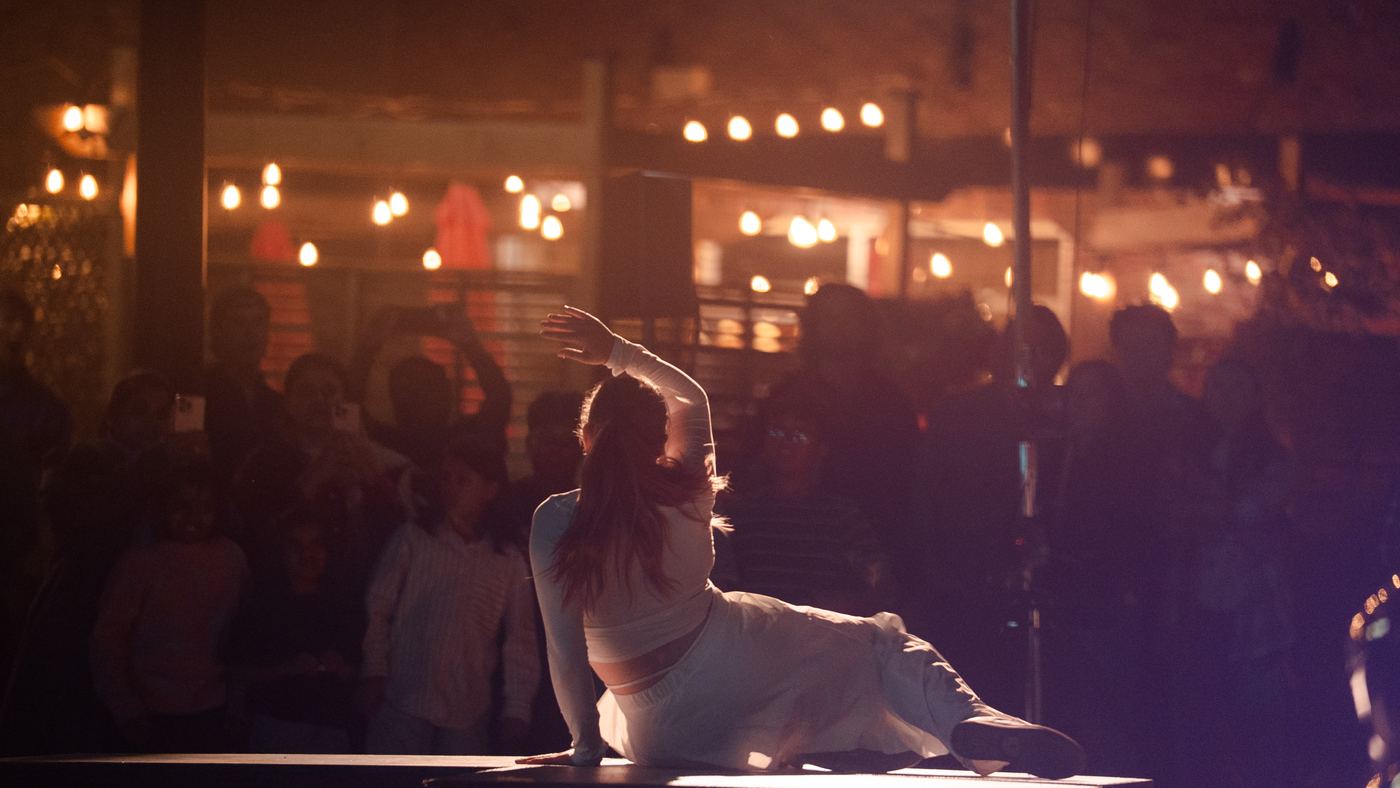A dancer low on a platform, the audience close behind