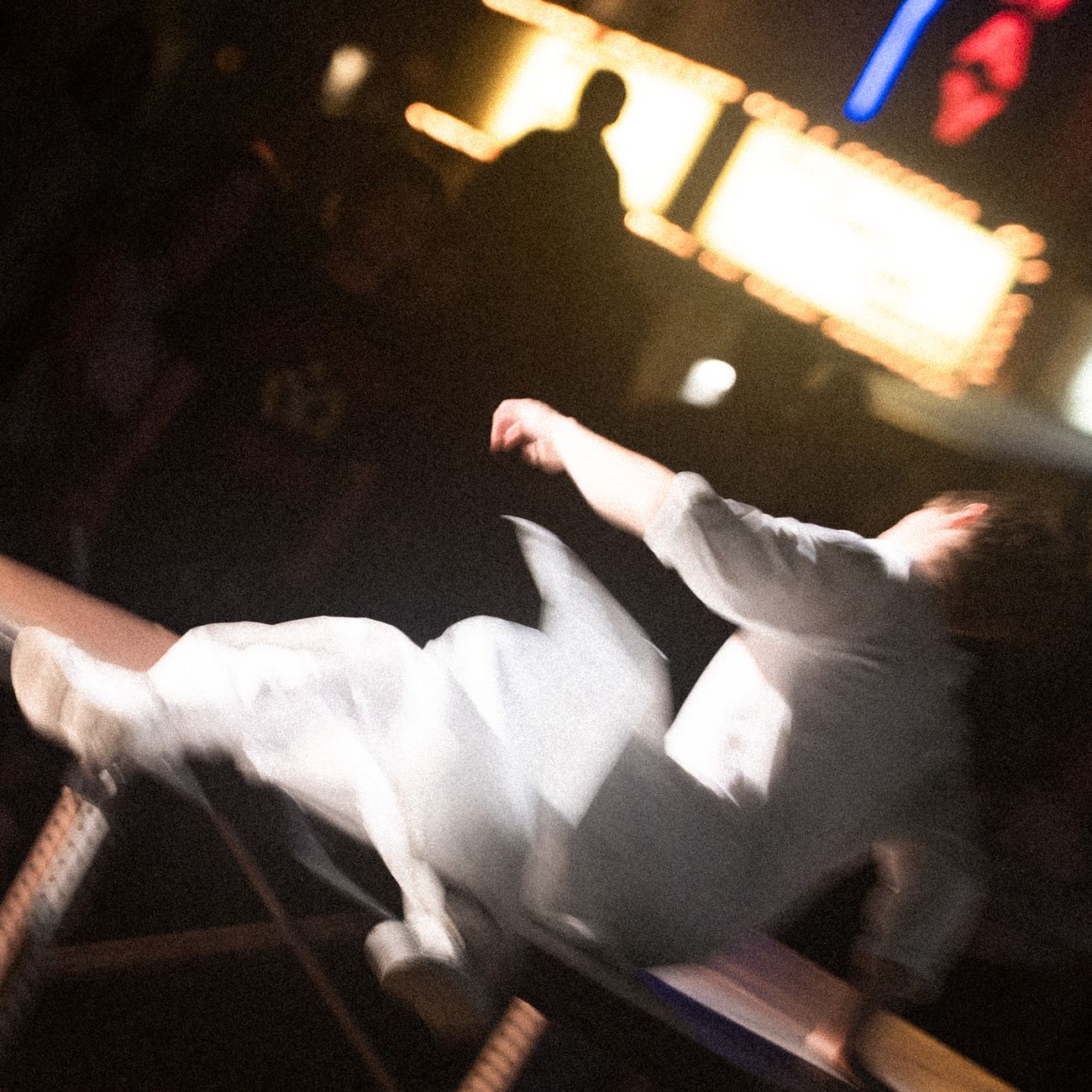 A dancer kicking off a platform under the theatre lights, blurred