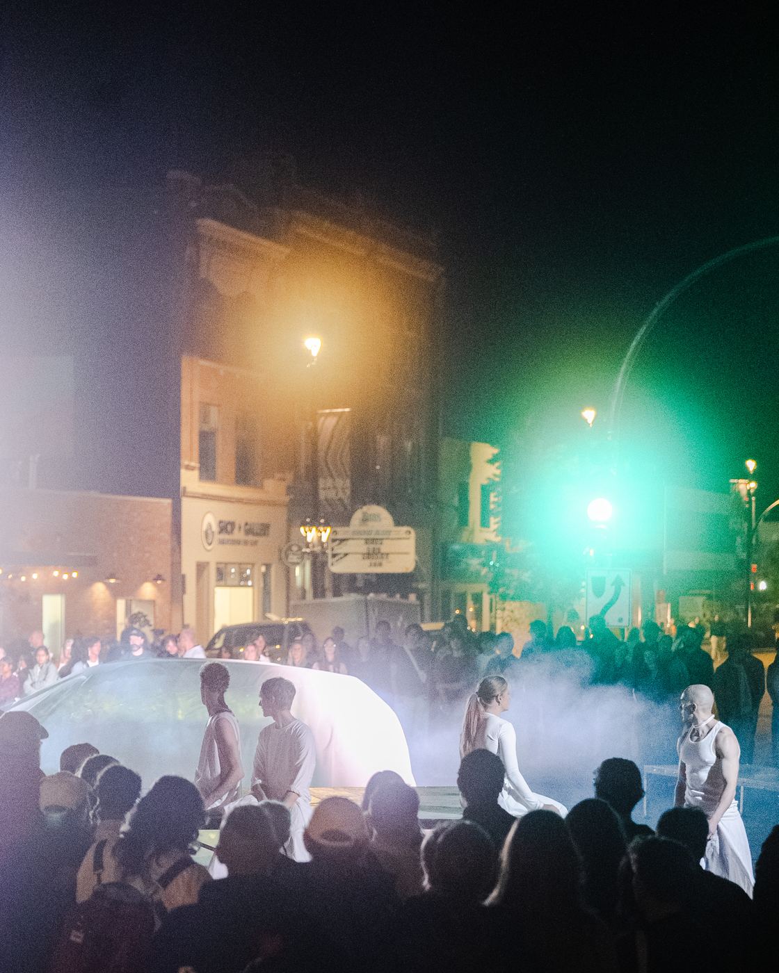 The crowd around the car in haze under a green traffic light