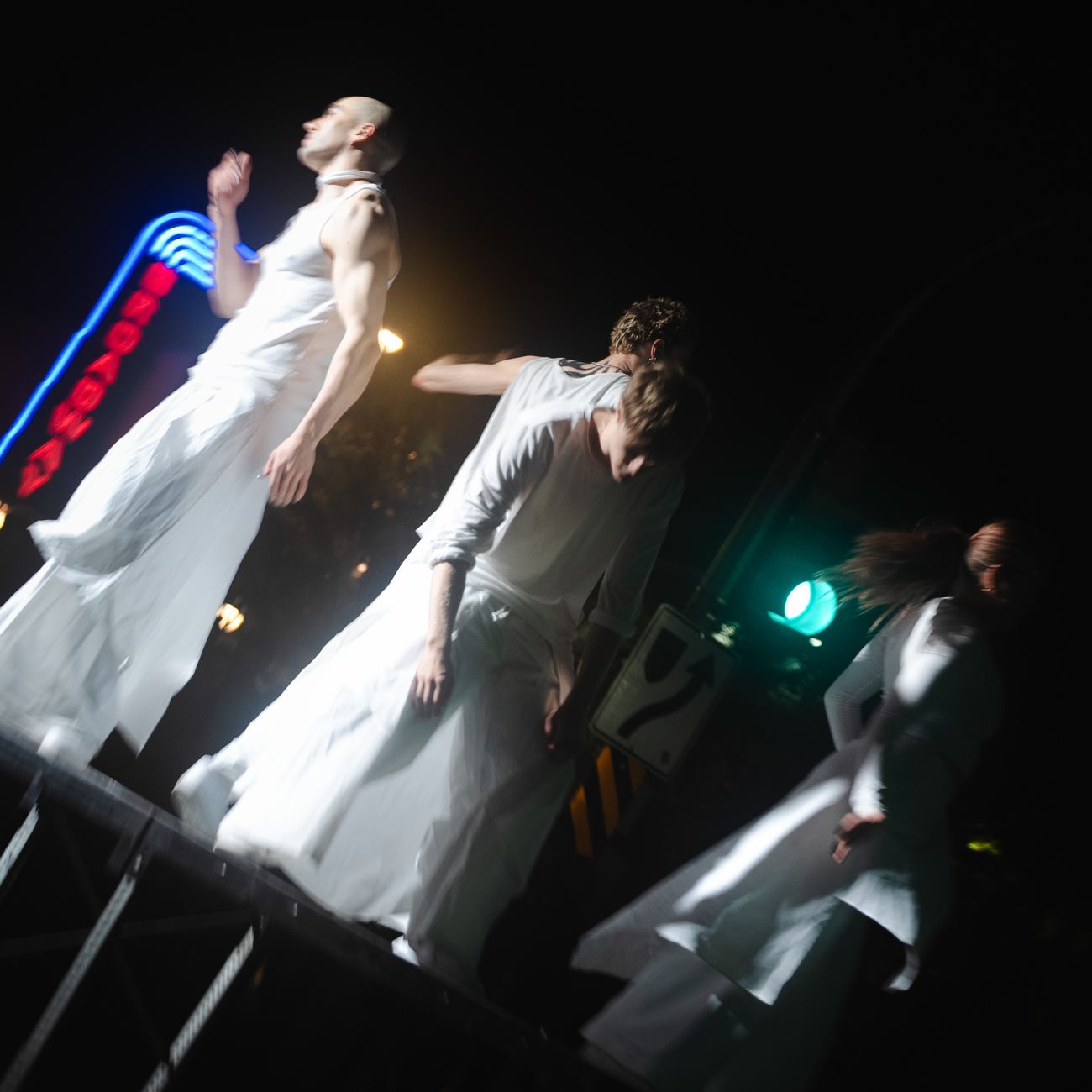Dancers leaning out from a platform under the Broadway neon sign