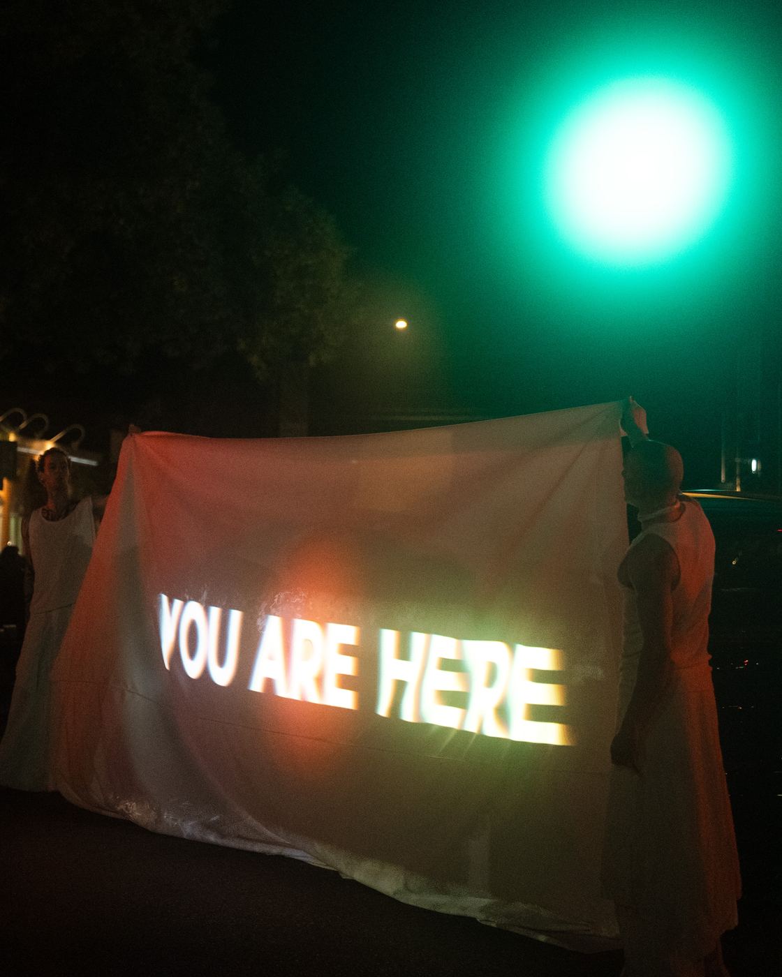 The words you are here projected onto white fabric held up by the performers, a green traffic light above