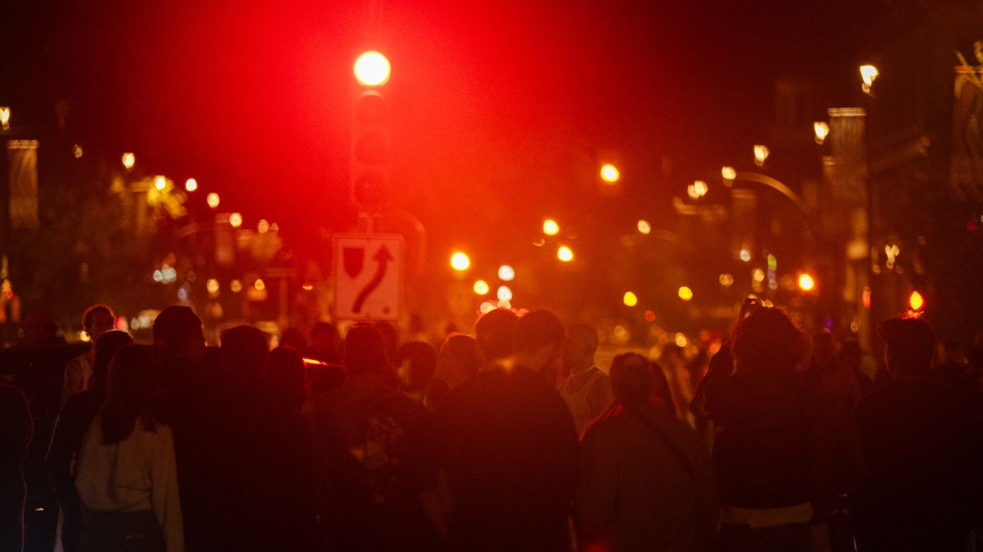 The street at night in red light, the crowd from behind